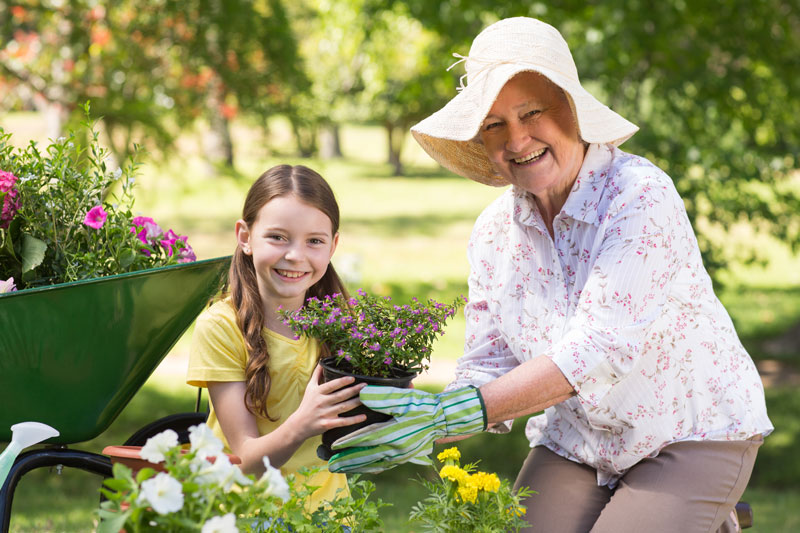 Photo of elderly woman gardening with child