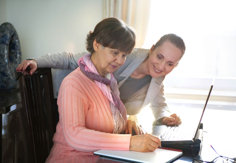 Photo of woman helping older woman on the computer